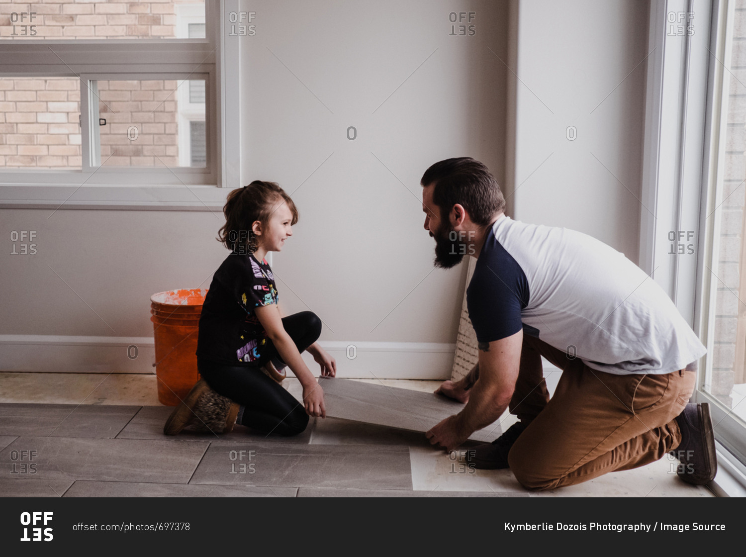 Girl helping father install floor tiles