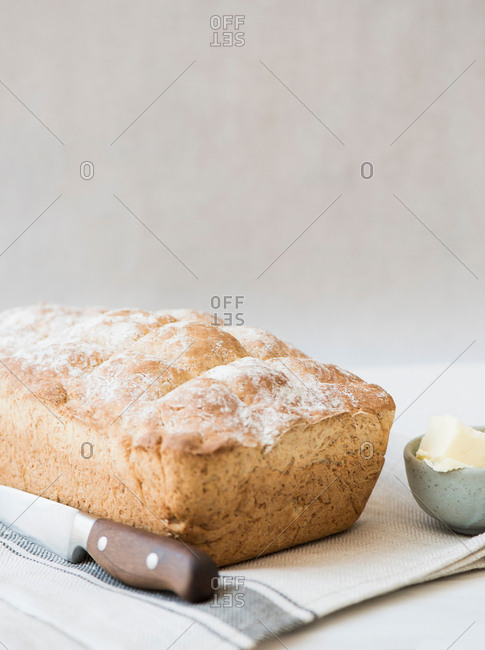 Freshly baked loaf of whole wheat bread with knife and butter