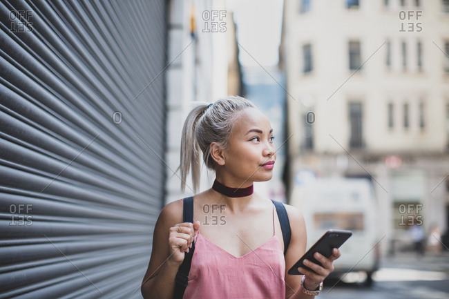 Young adult female walking and holding smartphone