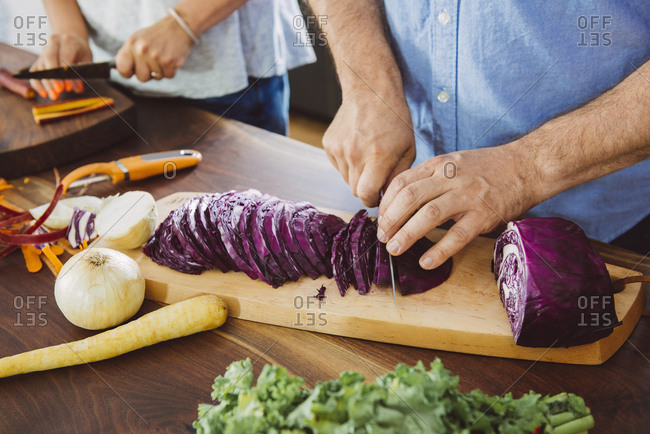 Cropped image of man cutting cabbage on board in kitchen