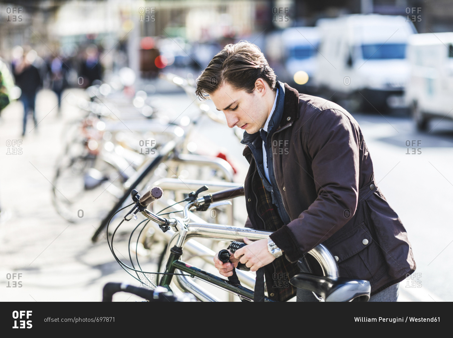 Businessman locking bicycle in the city