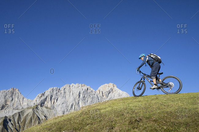 Mountain biker riding on uphill in alpine landscape, Tyrol, Austria