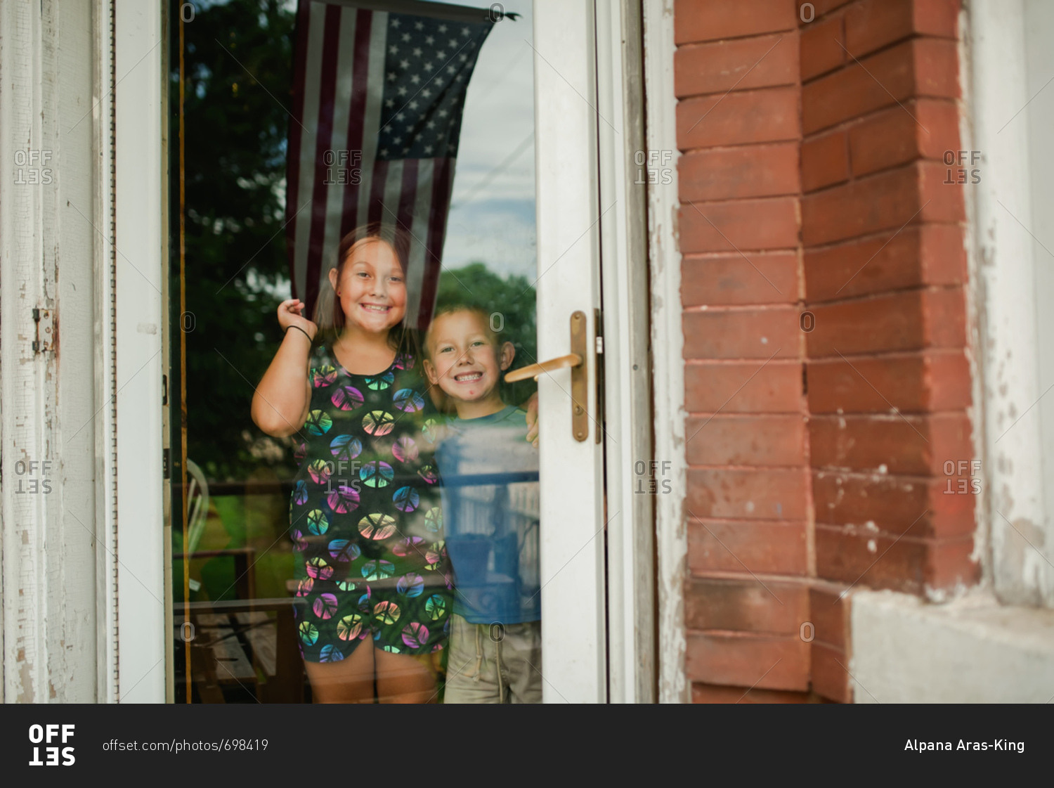 Portrait of children waving from a door in small town America