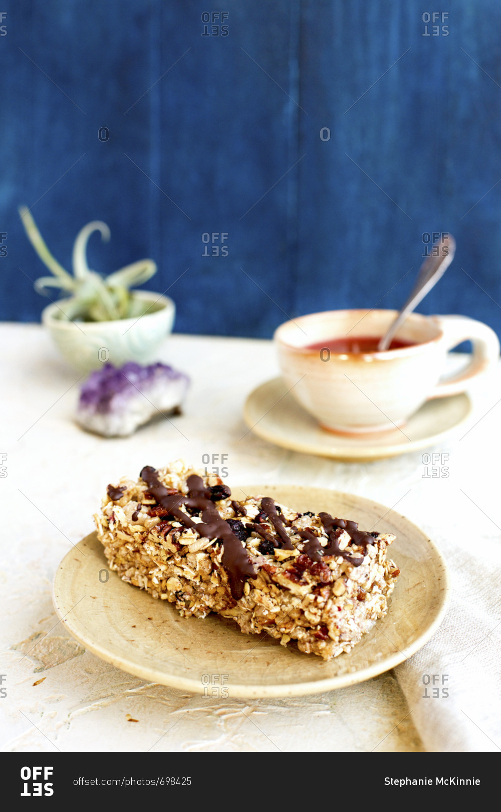 Blueberry caramelized pecan breakfast bar drizzled with dark chocolate served with a cup of tea
