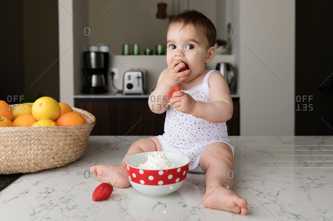 Baby sitting on kitchen counter with strainer on his head Stock Photo