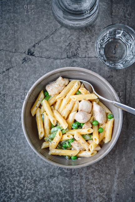 Top down view of rich creamy penne pasta with chicken and green peas