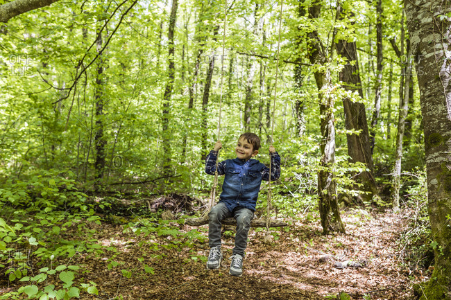 Happy kid on a swing amid a mountain trail