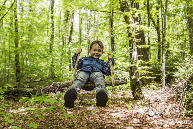 Happy kid on a swing amid a mountain trail
