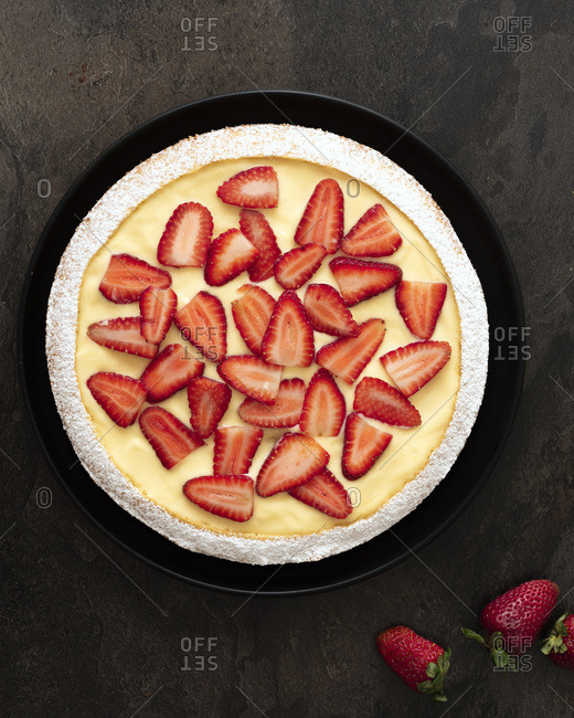 Strawberry and custard dessert cake on a black plate.