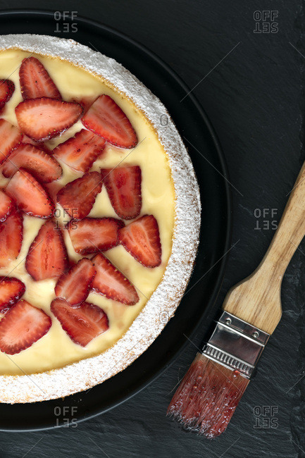 Strawberry custard dessert cake with a pastry brush.