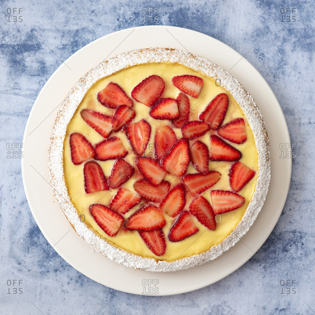 One large round strawberry custard dessert cake on a plate.