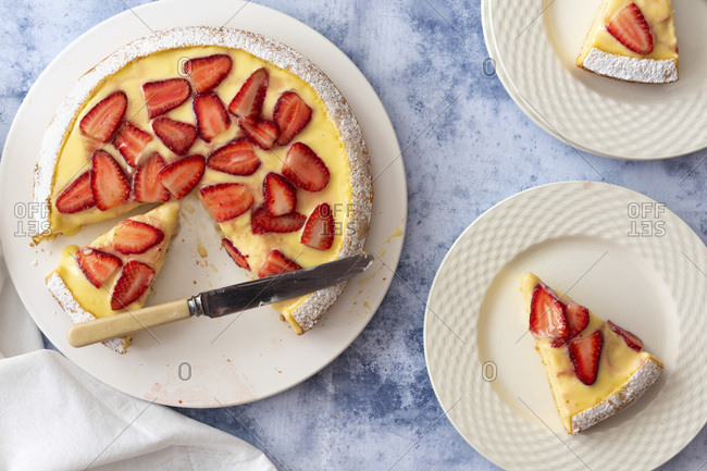 Strawberry Custard dessert cake with a knife and two serves on cake on plates.