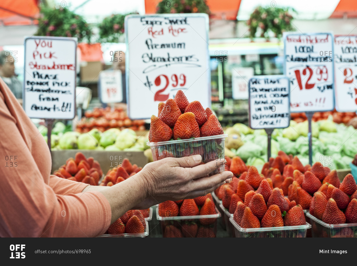 Close up of person holding punnet of fresh strawberries at a fruit and vegetable market
