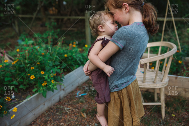 Sweet siblings standing in rural backyard together