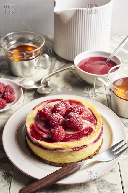 Mini cheesecake with swirl of raspberry sauce topped with fresh raspberries for tea break