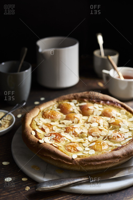 Apricot tart with custard, sweet yeast dough and sliced almonds on dark rustic table