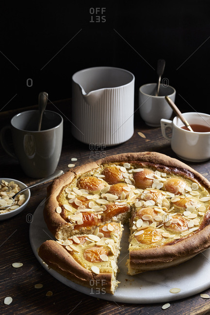 Apricot tart with custard and sweet yeast dough with a piece cut on dark rustic table