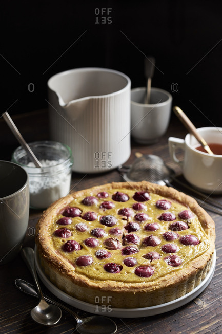 Red gooseberry tarte with custard and sweet yeast dough on dark rustic table