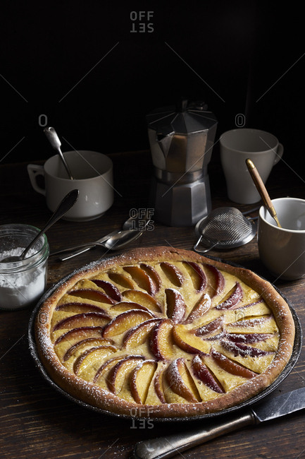 Peach tart with custard and sweet yeast dough on dark rustic table