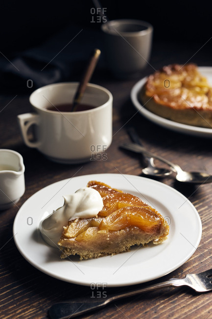 Cut slice of homemade apple tarte tatin with whole tart in the background