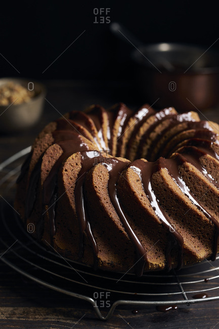Garnishing homemade hazelnut bundt cake with chocolate ganache and chopped hazelnuts