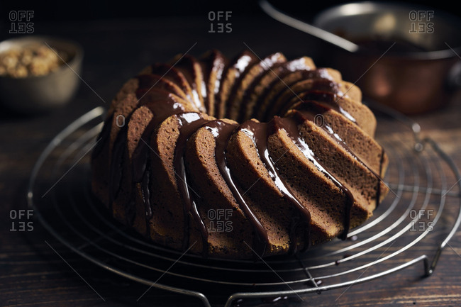 Garnishing hazelnut bundt cake with chocolate ganache and chopped hazelnuts