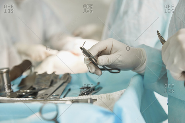 Midsection of surgeon holding surgical scissors during surgery at hospital