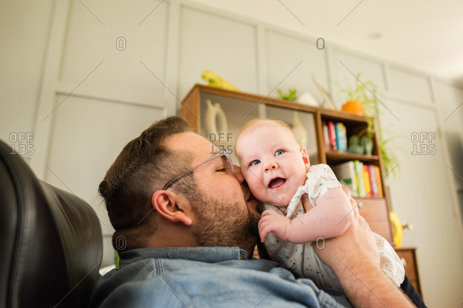 Father holding infant daughter and kissing her cheek