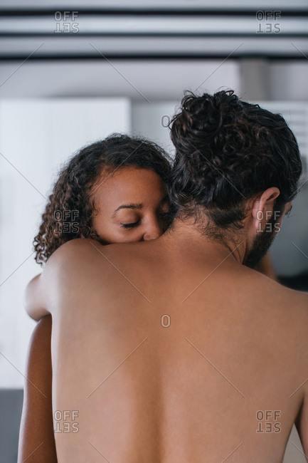 Rearview of young couple hugging in kitchen