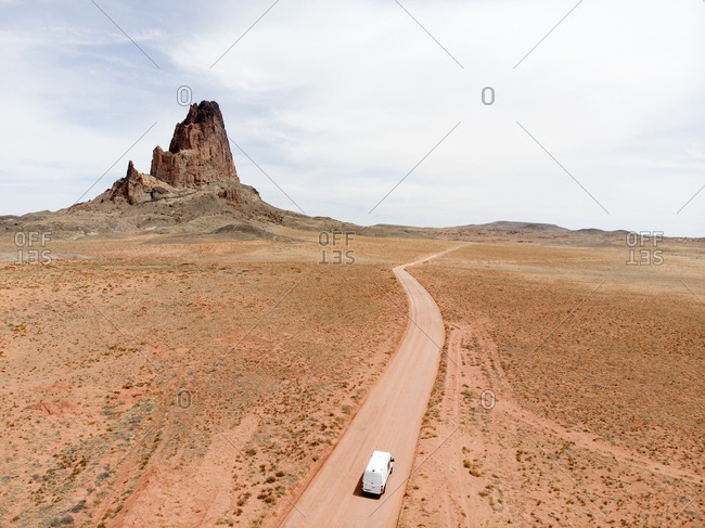Aerial view of van driving on dirt road leading to horizon with butte in the background in Monument Valley, Arizona