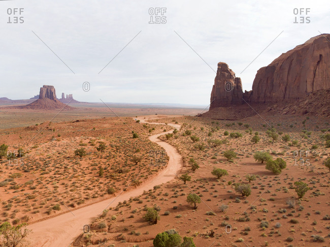 High angle view of dirt road leading to horizon past iconic buttes in Monument Valley, Arizona
