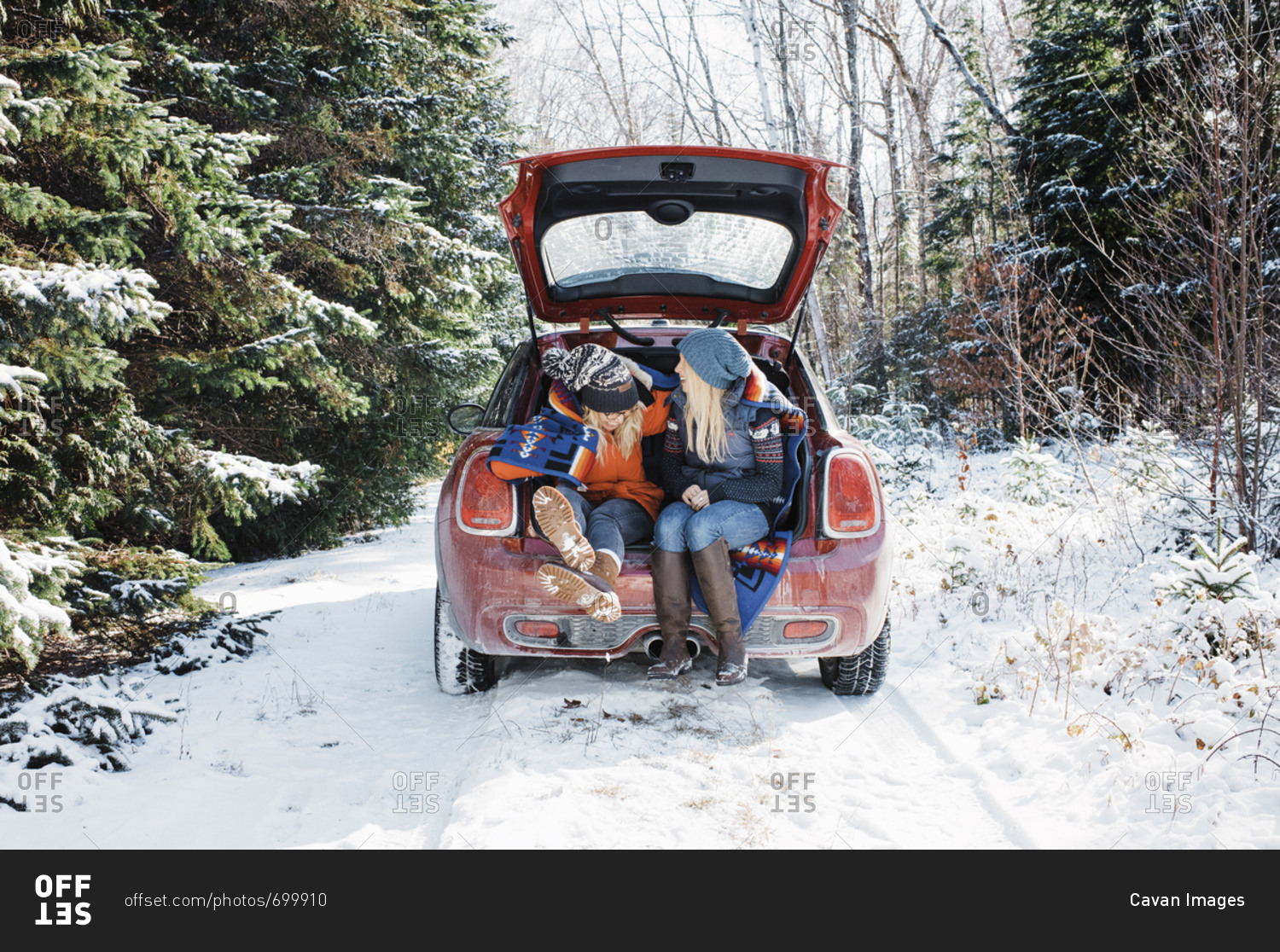 Female friends sitting in car trunk at Algonquin Provincial Park during winter