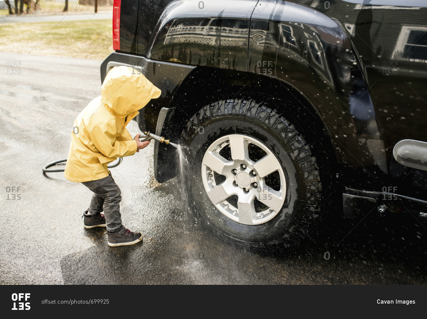 Boy cleaning sports utility vehicle on road