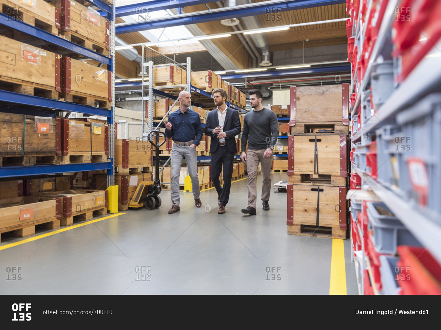 Three men walking and talking in factory storeroom