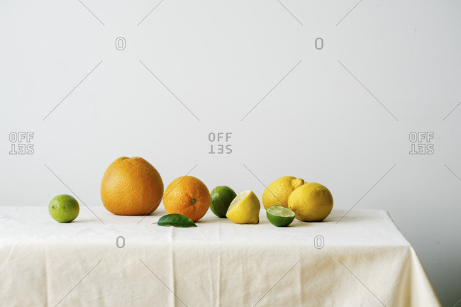Minimalistic composition with citrus fruits on a table covered with white linen tablecloth