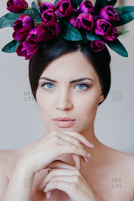 Portrait of beautiful brunette woman with blue eyes with purple tulips on her head