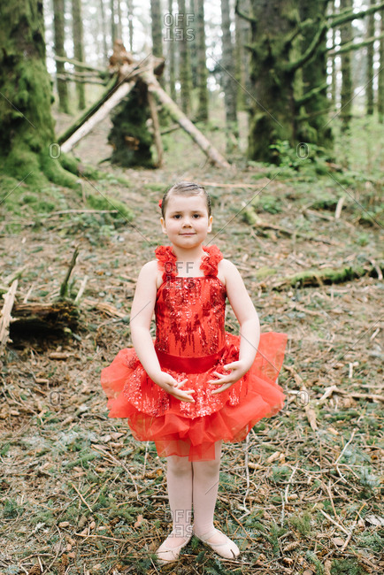 Little girl in a red ballet outfit in the woods