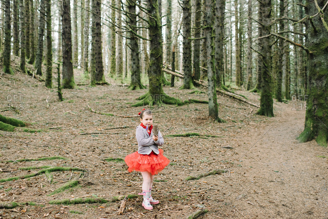 Young girl in a red ballet outfit walking in the woods
