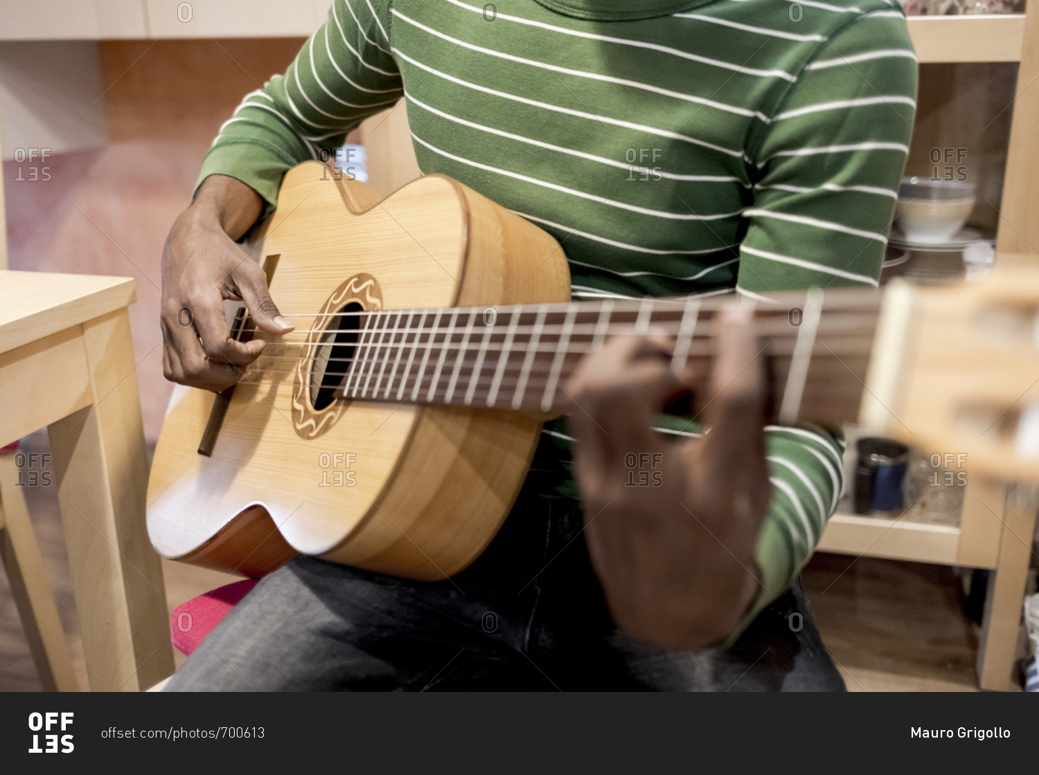 Close up of a Brazilian man playing an acoustic guitar at home