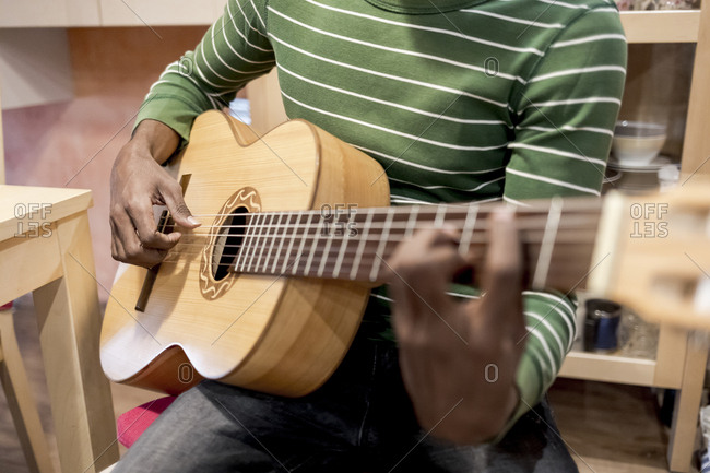 Close up of a Brazilian man playing an acoustic guitar at home