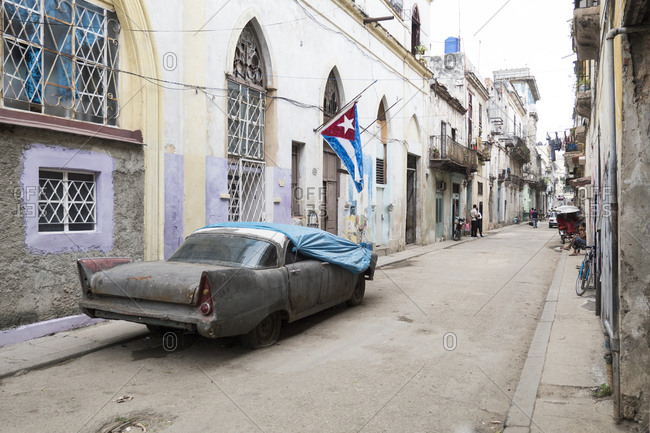 Havana, Cuba - March 25, 2015: Derelict antique car covered in tarp parked in residential street