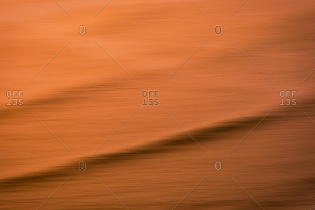 Abstract image of swell lines moving through ocean colored by setting sun