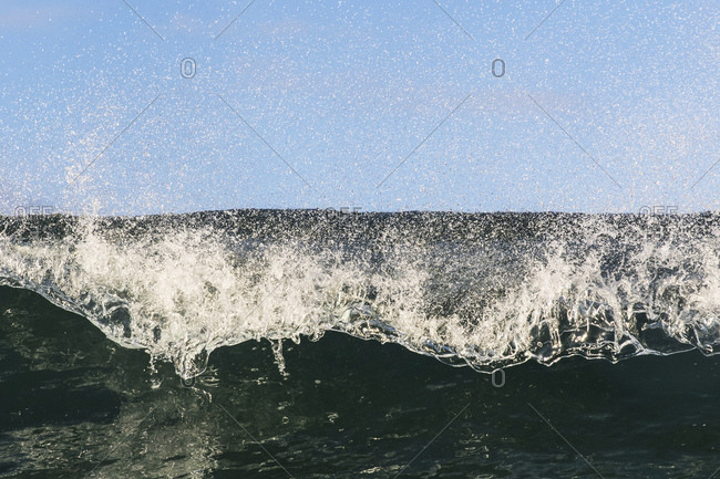 Water shot of wind blowing spray off the top of breaking wave