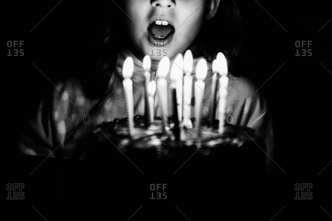 Girl blowing out birthday candles in black and white
