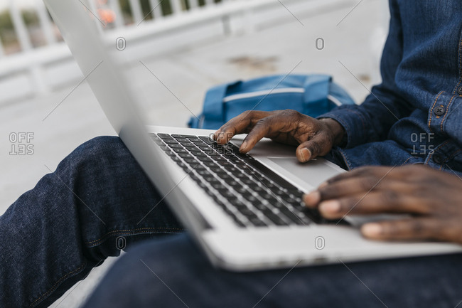 Hands of african man working with laptop at outdoors in Barcelona