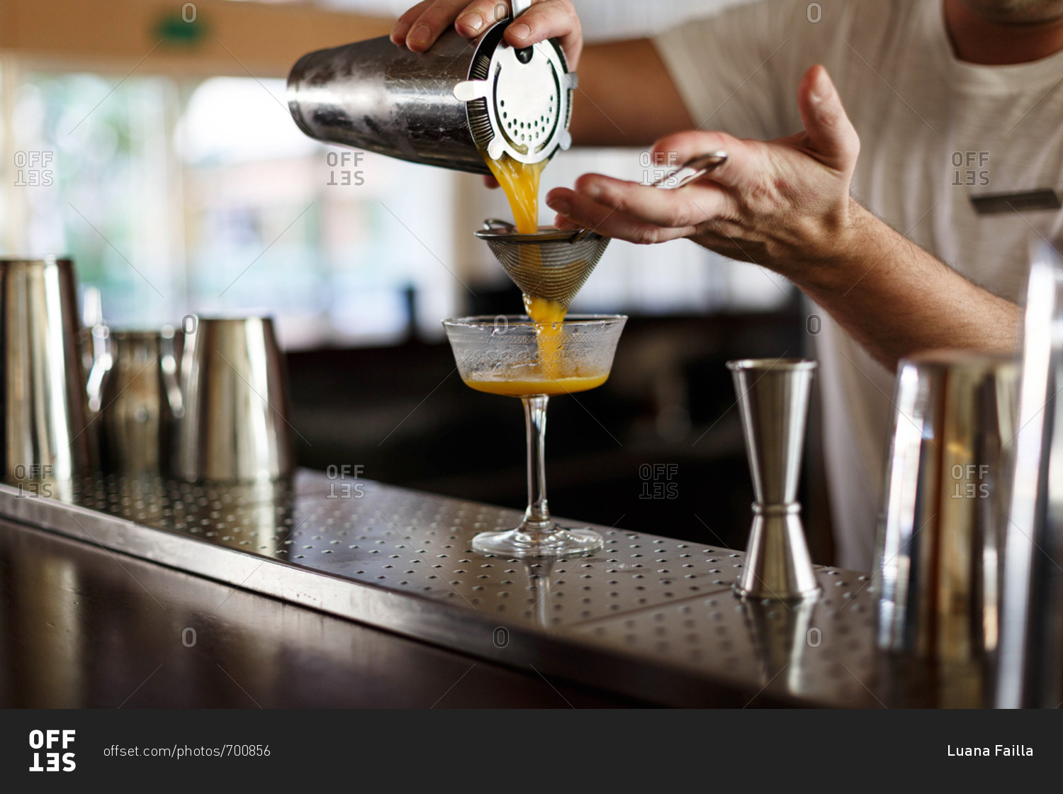 Bartender pouring orange juice through strainer stock photo OFFSET