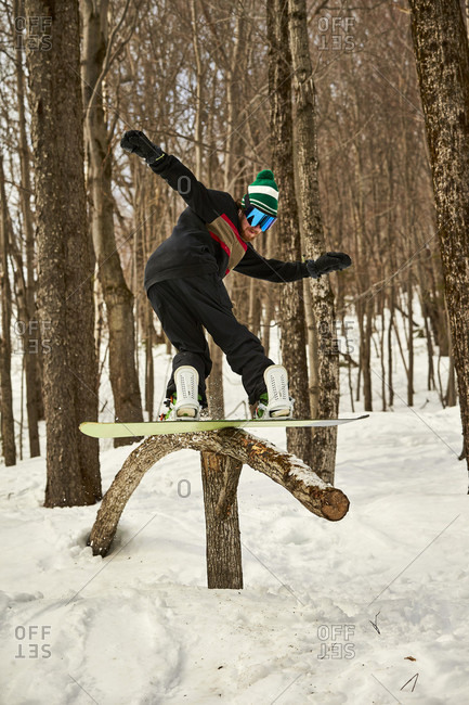 Snowboarder sliding on wooden feature in terrain park, Vermont, USA