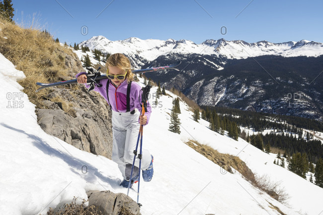 Young girl carrying skis up snowy hill before skiing in Molas Pass, Silverton, Colorado, USA