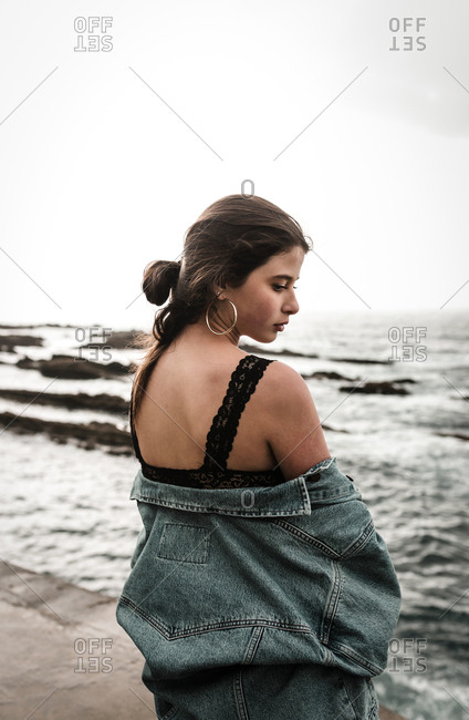 Lonely woman looks over shoulder in silence on overcast beach day trip
