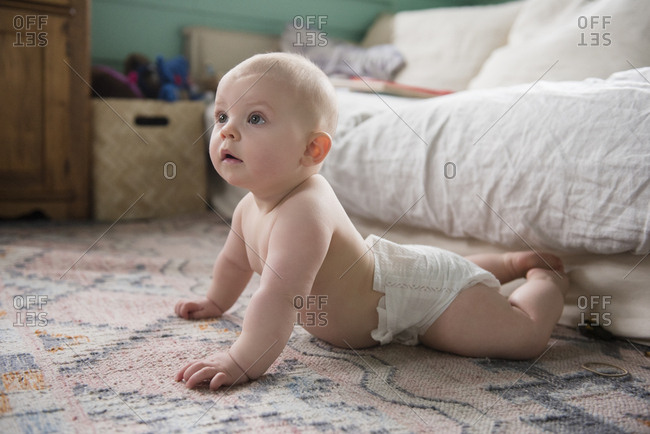 Baby girl (12-17 months) on carpet near sofa